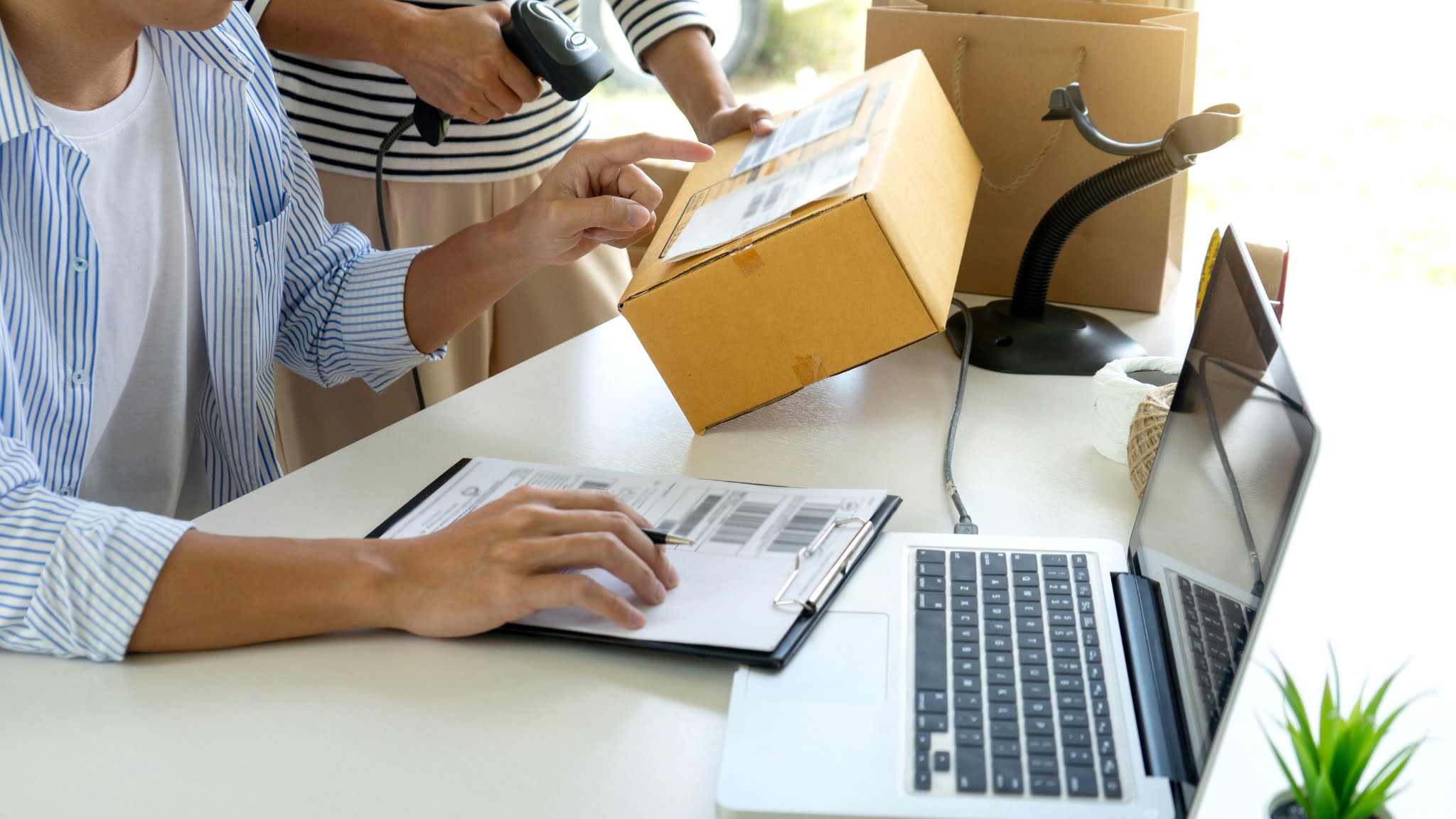 A man and woman working on a laptop and a box, checking inventory.