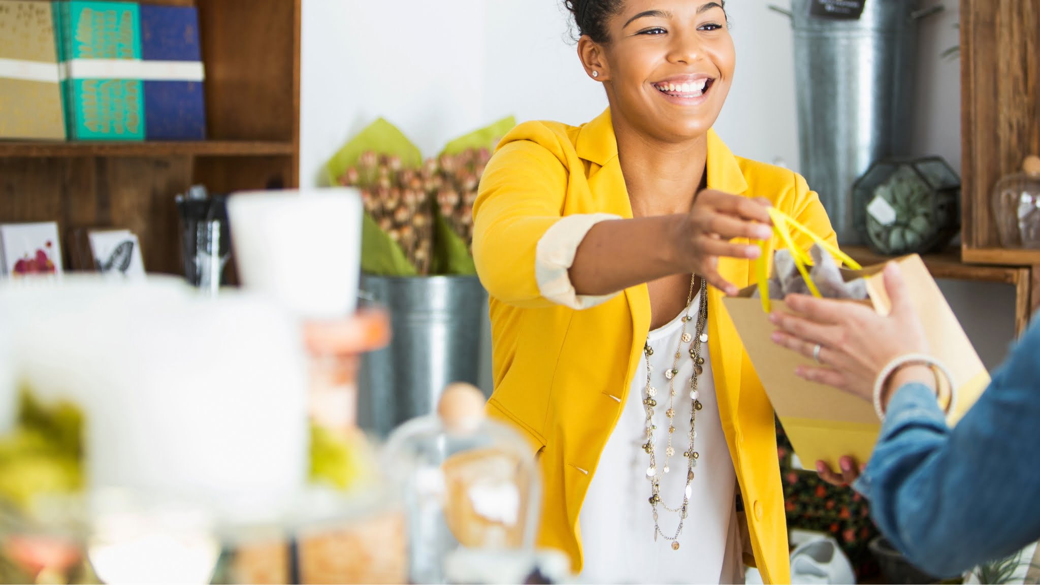 Woman passing a gift to another woman, both smiling. Transaction of a sold product