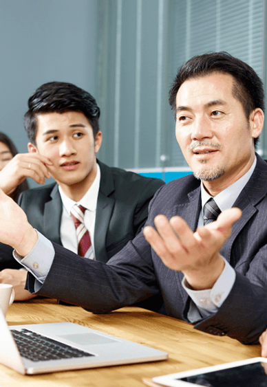 A diverse group of people sitting at a table, listening attentively as their boss leads a discussion