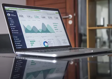 A laptop on a desk displaying sales analytics graphs.