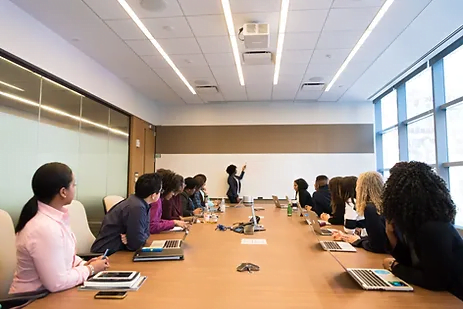 A large team meeting with people sitting around a conference table