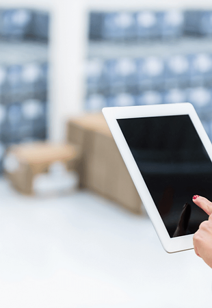 A person using a tablet computer in a warehouse, tapping on the screen