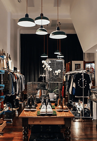 A clothing store with a wooden floor and lots of clothes, in an apparel shop.