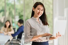 A smiling woman in a business suit holding a laptop